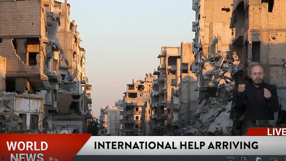 A live newscast with the sign-language interpreter small in the bottom-right corner, above the news ticker.